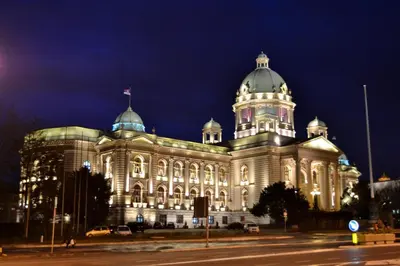 a large building with a flag on top of it at night at Belvedere city center apartment in Belgrade