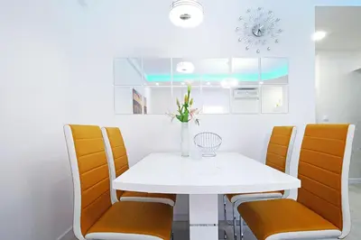 a dining room with a white table and orange chairs at Apartment Paradise SunShine in Belgrade