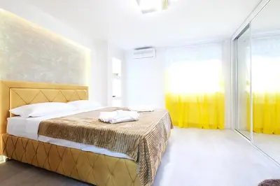 a bedroom with a large bed with yellow curtains at Apartment Paradise SunShine in Belgrade