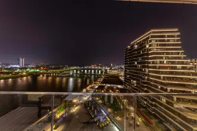 a tall building next to a river at night at Queen Apartments Belgrade Waterfront in Belgrade