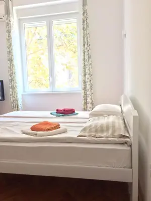 a white bed with a window and two towels on it at Cricket Park Hostel in Belgrade
