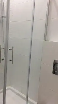 a shower with a glass door in a bathroom at Cricket Park Hostel in Belgrade
