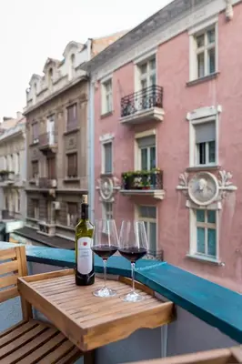 two glasses of wine sitting on a table on a balcony at Delights Apartment Belgrade in Belgrade