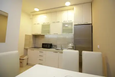 a kitchen with white cabinets and a stainless steel refrigerator at Luna Lux Apartman in Belgrade