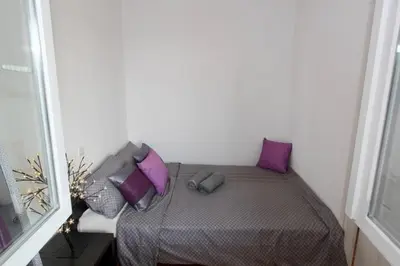 a small bedroom with a bed with purple pillows at Cezar Apartment in Belgrade