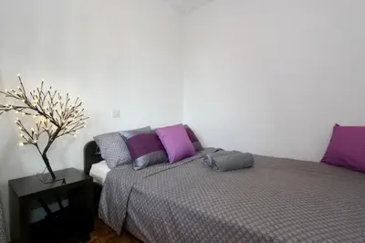 a bedroom with a bed with purple and purple pillows at Cezar Apartment in Belgrade