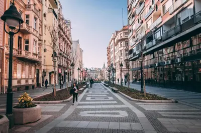 a woman walking down a city street with buildings at Brigitte's Central in Belgrade