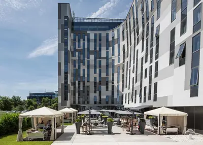 a building with tables and umbrellas in front of it at Zijin Hotel Belgrade in Belgrade