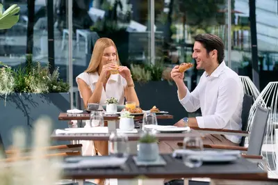 a man and woman sitting at a table eating food at Zijin Hotel Belgrade in Belgrade