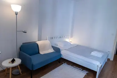 a small bedroom with a blue bed and a chair at DOWNTOWN STUDIO AP in Belgrade