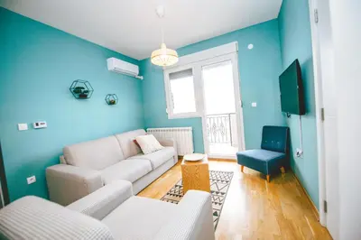 a living room with a white couch and a blue wall at Lola Almost Home in Belgrade