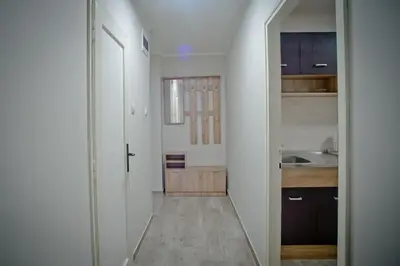 a hallway leading to a kitchen with white walls at Park Apartman in Arandjelovac