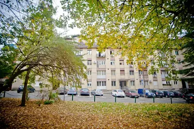 a large building with cars parked in a parking lot at Park Apartman in Arandjelovac
