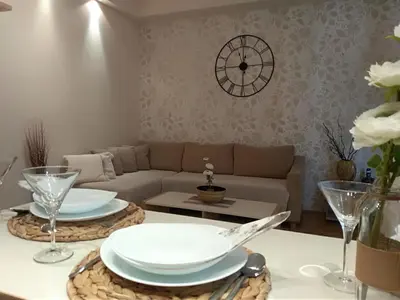 a living room with a couch and a table with plates at Apartman Nina Vojvode Stepe Vozdovac in Voždovac