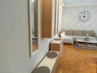 a living room with a white couch and a mirror at Apartman Nina Vojvode Stepe Vozdovac in Voždovac