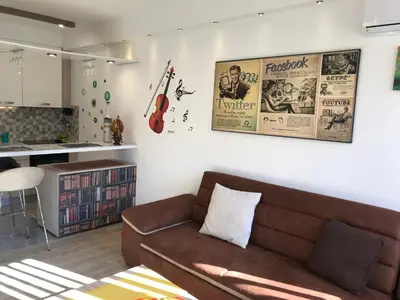 a living room with a brown couch and a kitchen at Lovely Apartment 2 in Belgrade