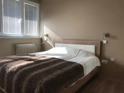 a bedroom with a bed with a blanket and two windows at Lovely Apartment 2 in Belgrade