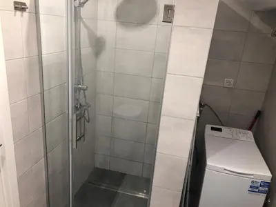 a shower with a glass door next to a washer at La Fontana in Belgrade