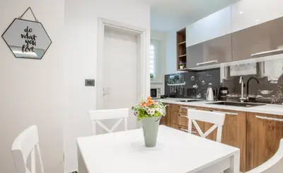 a white kitchen with a table and a vase with flowers on it at Casablanca apartment in Belgrade