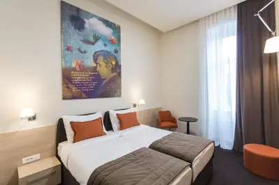 a hotel room with a bed and a painting on the wall at Hotel Grand Hedonist in Pančevo