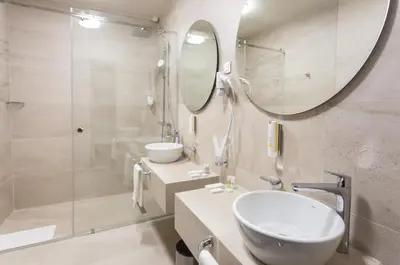 a bathroom with a sink and a shower and a mirror at Hotel Grand Hedonist in Pančevo