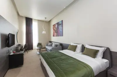 a hotel room with a large bed and a couch at Hotel Grand Hedonist in Pančevo