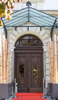 a large wooden door in a building with a red carpet at Hotel Grand Hedonist in Pančevo