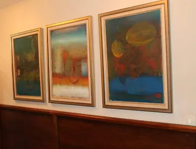 three framed paintings on a wall above a wooden cabinet at Villa Skadarlija in Belgrade