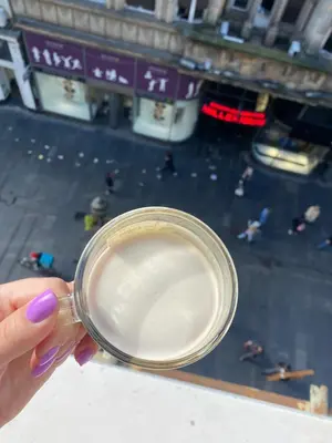 a hand holding a cup with a view of a city at Knez Mihailova Apartman in Belgrade