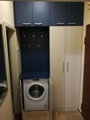 a washing machine in a kitchen with blue cabinets at BY THE PARK free parking in Belgrade