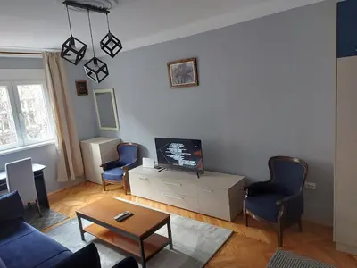 a living room with a tv and two blue chairs at BY THE PARK free parking in Belgrade