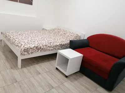 a room with a bed and a red couch at Airport view Apartment in Belgrade