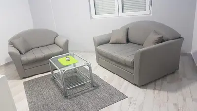 two chairs and a couch and a table in a living room at Airport view Apartment in Belgrade