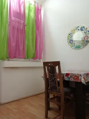 a chair sitting in front of a table with colorful curtains at Kiwi Apartment in Belgrade