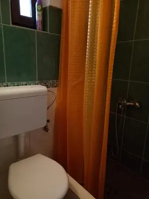 a bathroom with a toilet and an orange shower curtain at Tiki Apartmen in Belgrade
