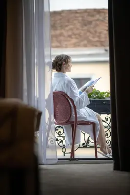 a woman sitting in a chair reading a book at Maison Royale in Belgrade