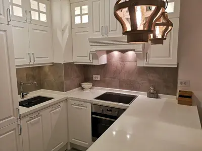 a kitchen with white cabinets and a sink and a chandelier at NIKLUK in Belgrade