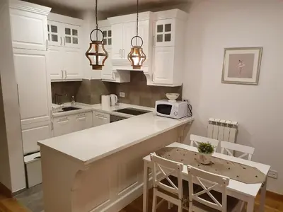 a kitchen with white cabinets and a table and chairs at NIKLUK in Belgrade
