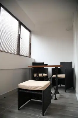 a room with a table and chairs and two windows at Havana Beograd Apartment in Belgrade
