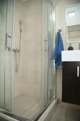 a shower with a glass shower stall next to a sink at Havana Beograd Apartment in Belgrade