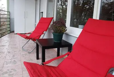 two red chairs and a table on a porch at Arena Apartman in Belgrade