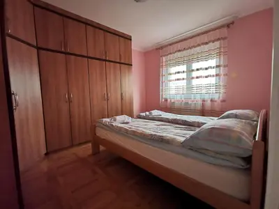 a bedroom with a bed and wooden cabinets and a window at Apartman White in Belgrade