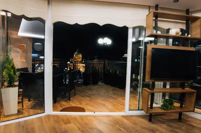 a living room with a tv and a balcony at night at President Lux in Belgrade
