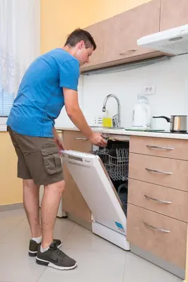 a man opening an open dishwasher in a kitchen at SAN 011 in Belgrade