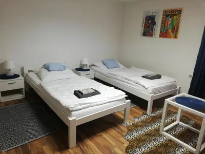 two twin beds in a room with wooden floors at Apartman Romy in Pančevo