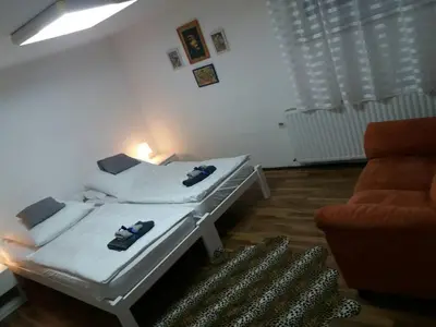 a white room with a bed and a chair at Apartman Romy in Pančevo