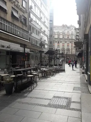 an empty city street with tables and chairs and buildings at Apartment Ema in Belgrade
