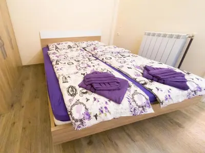a bed with purple sheets and purple pillows on it at Apartment Ema in Belgrade