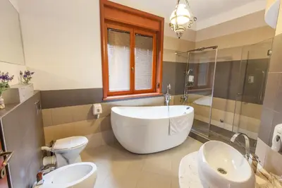 a bathroom with a tub and a toilet and a sink at The Belgrade Hills Rooms and Suites in Belgrade