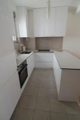 a white kitchen with white cabinets and a tile floor at Apartman Nodilova in Belgrade